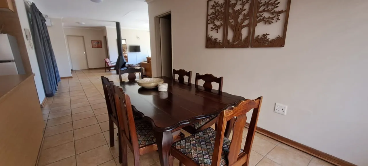 Elegant wooden dining table set and chairs in the open-plan dining and lounge area at Bloom Guest House in Dan Pienaar, Bloemfontein.